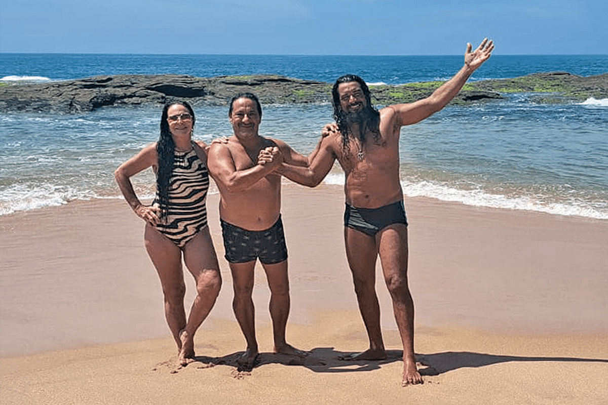 Kaká Kilha, ao centro, com sua esposa Regina e o pescador Max Schimidt, o “Guardião das Pedrinhas”. Kaká fez parte dos surfistas que desbravaram a Praia das Pedrinhas na adolescência, quando surfava e, hoje, vai caminhando com o filho e a esposa.